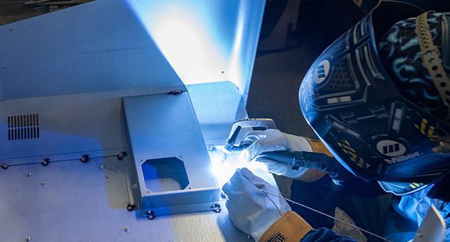 Blue sparks fly from a person manually welding sheet metal