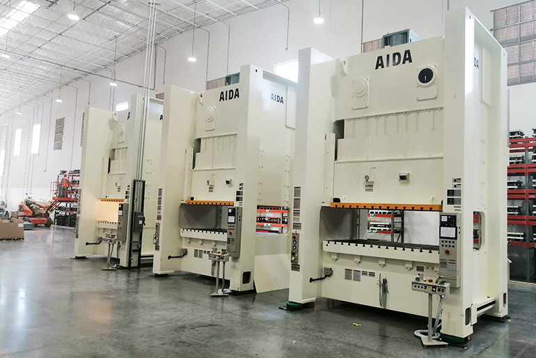 Three large sheet metal stamping presses in a line