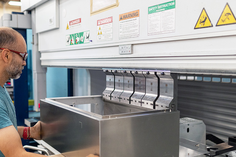 Man using press brake to fabricate a sheet metal enclosure