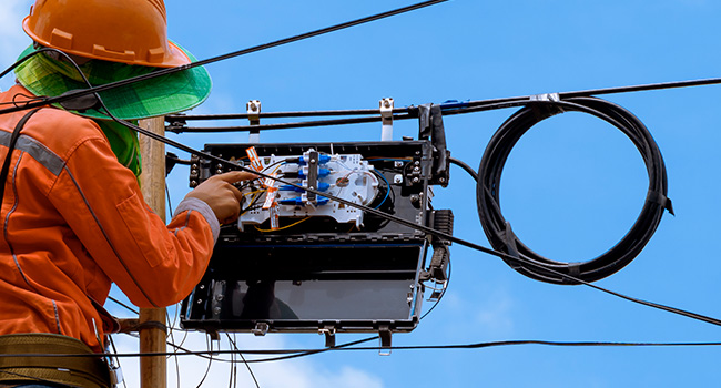 Person working on fiber panel mounted on telephone poll