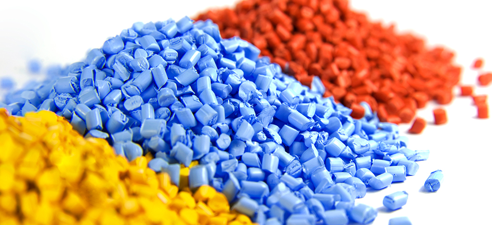 Three piles of injection molding grind material in red, blue, and yellow